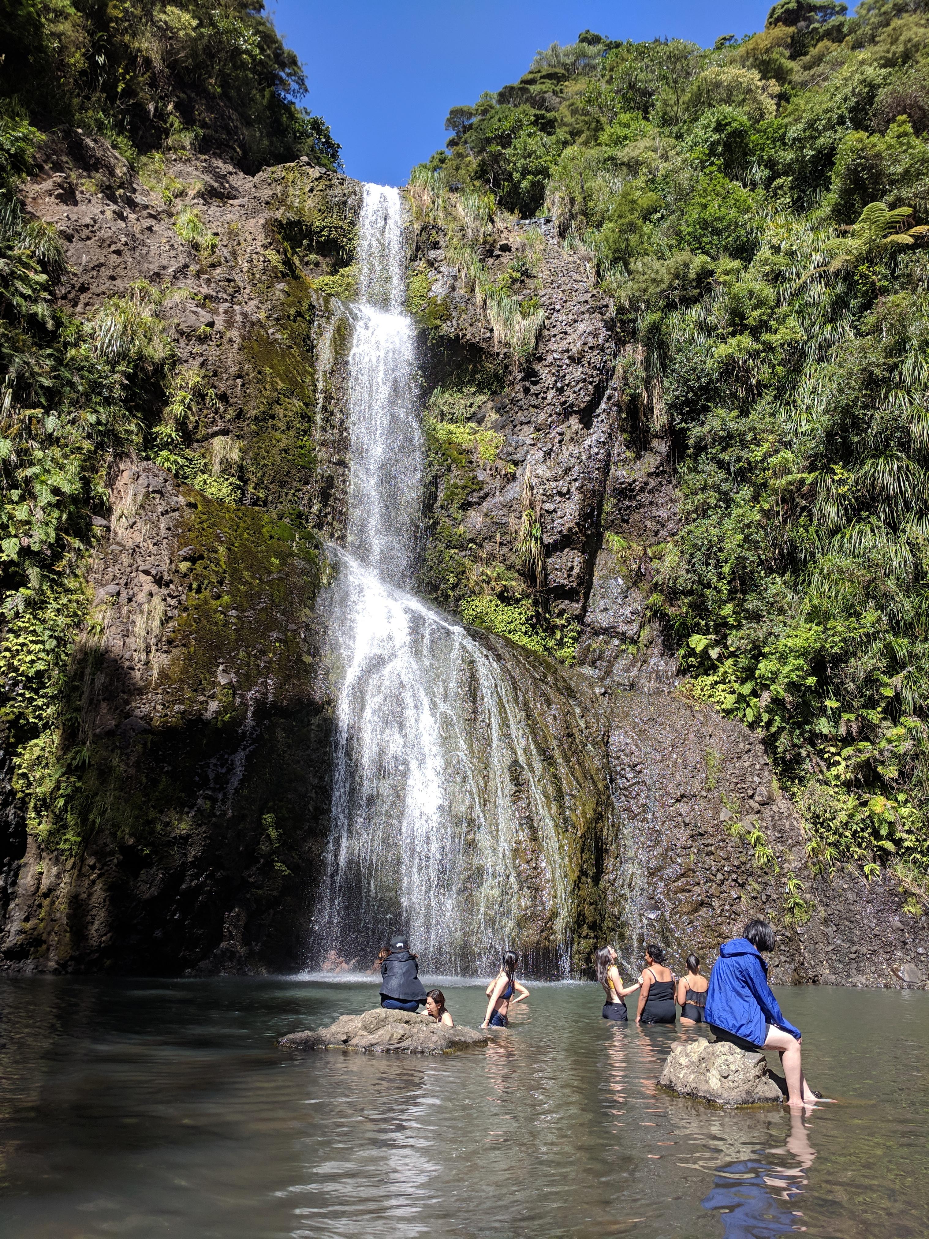 People swimming at the base of Kitekite falls
